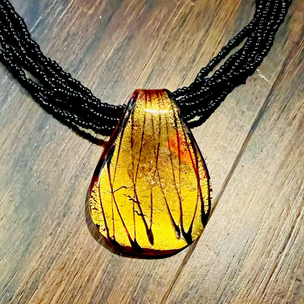 Multi strand, black bead necklace with blown glass pendant.